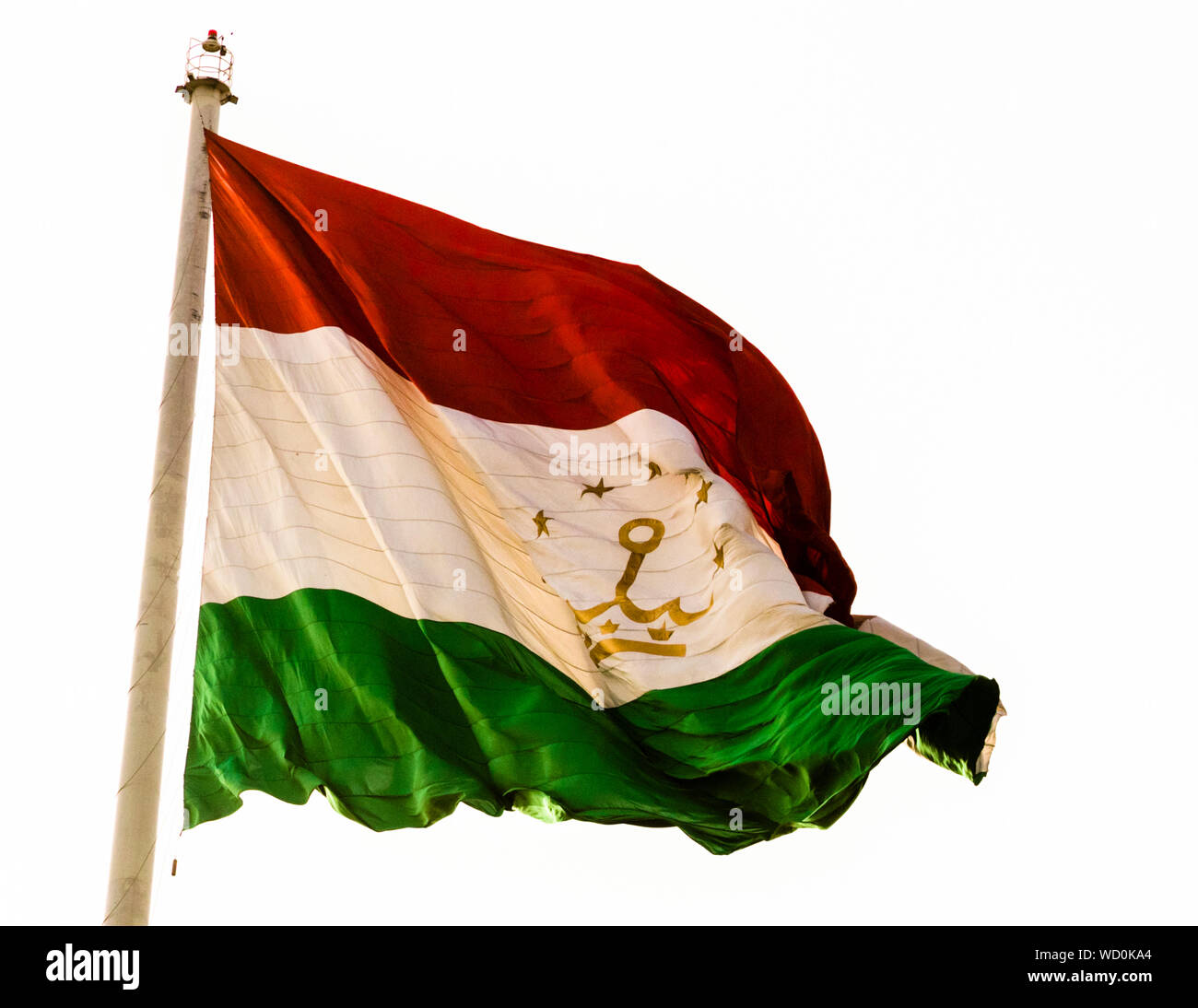 A golden crown and stars decorate the flag of Tajikistan flying on a 165-meter flagpole in Dushanbe in Rudaki- Park of Dushanbe, Tajikistan Stock Photo