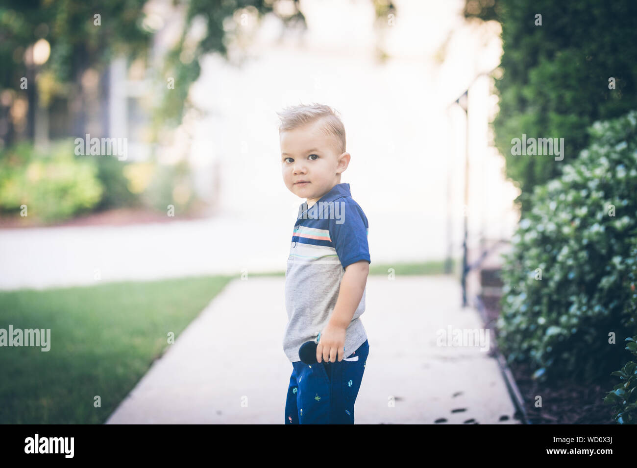 Little boy looking at camera over his shoulder outdoors Stock Photo
