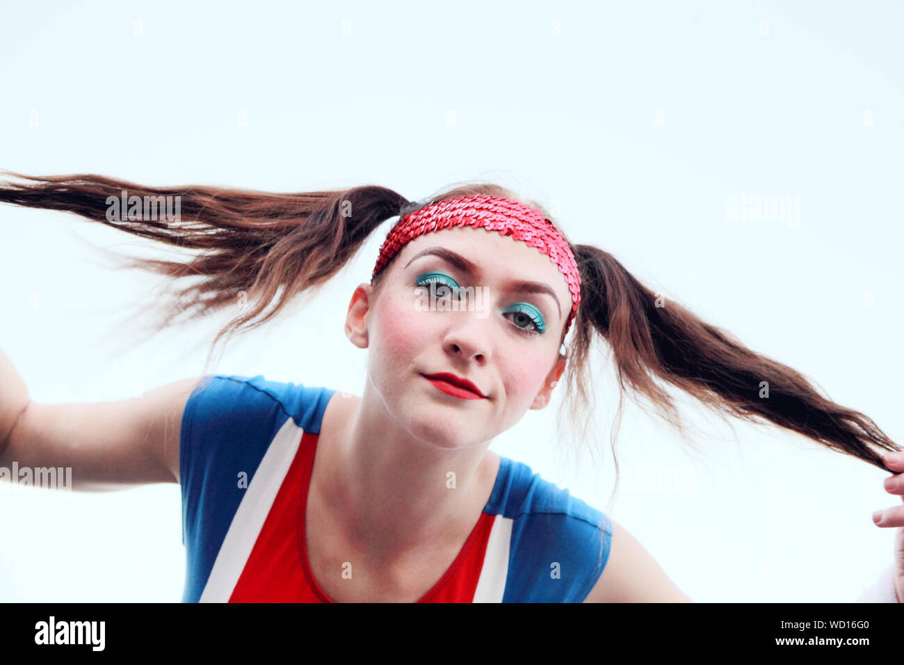 Portrait Of Cheerleader Pulling Ponytails Against White Background