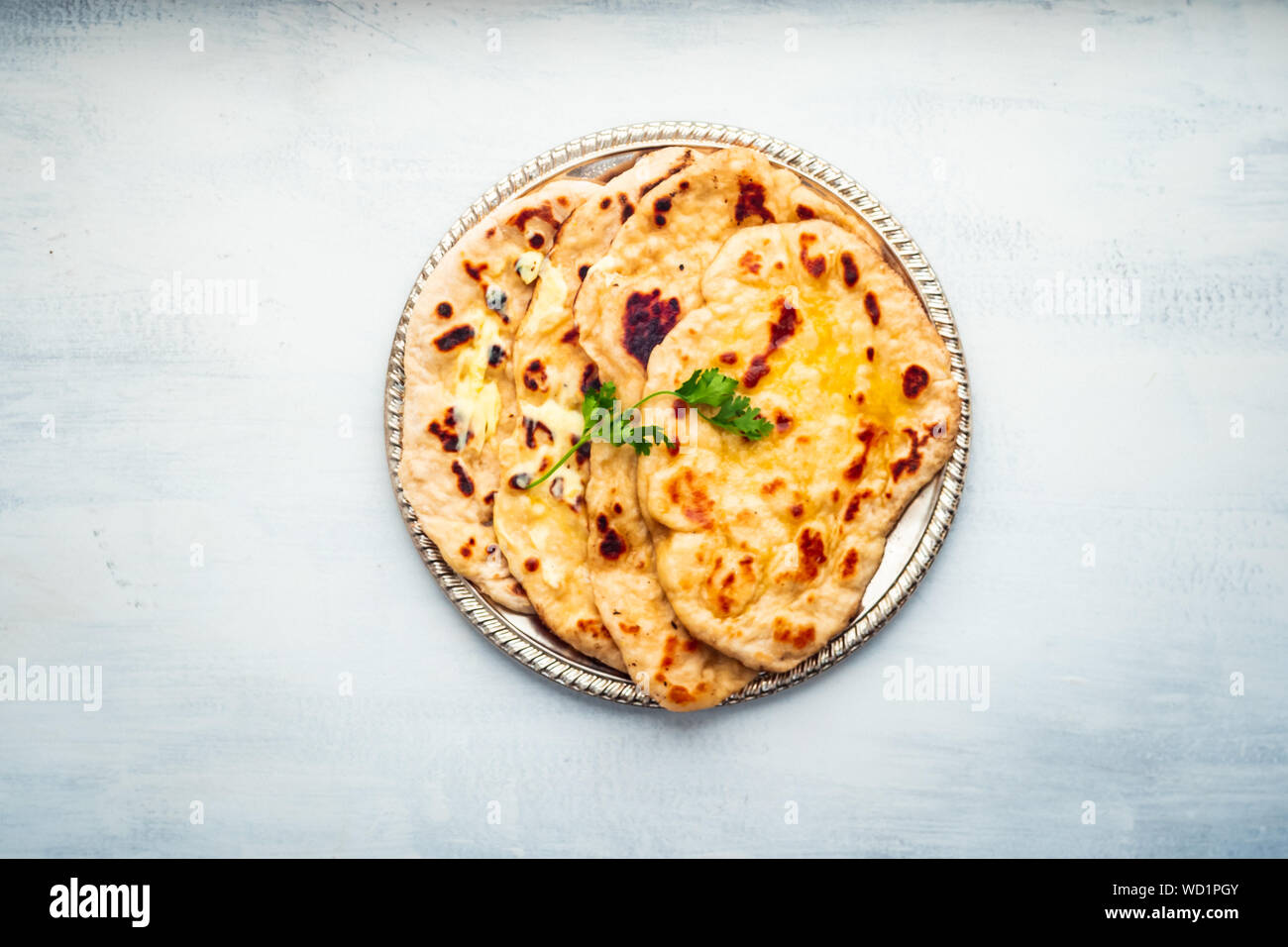 Indian Food: Naan Bread Dish with Butter and Cilantro Leaf, Served on a Rustic Metal Tray Stock Photo