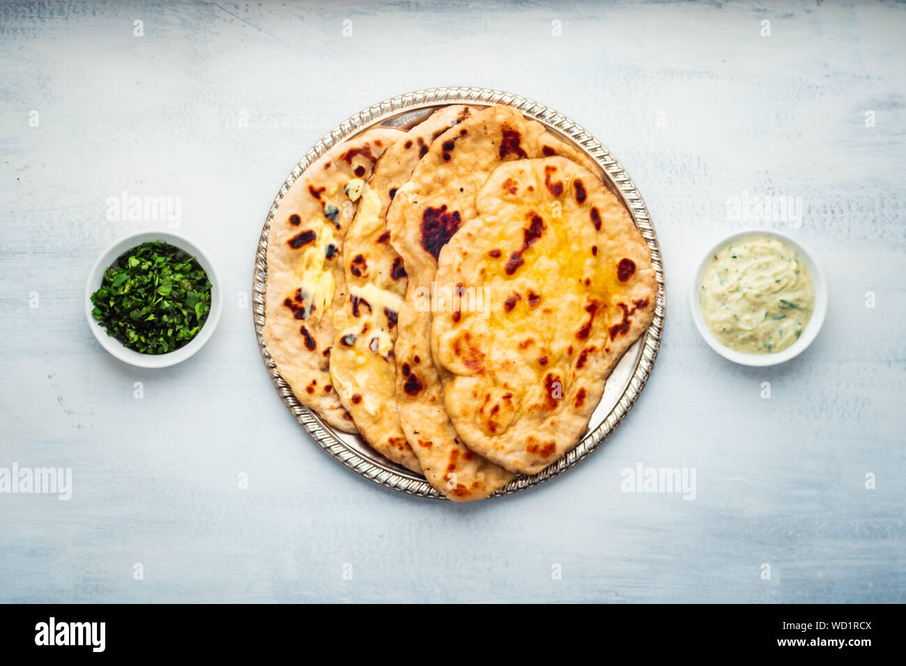 Indian Food: Naan Bread Dish with Butter, Served in a Rustic Metal Tray with Coriander and Raita. Stock Photo