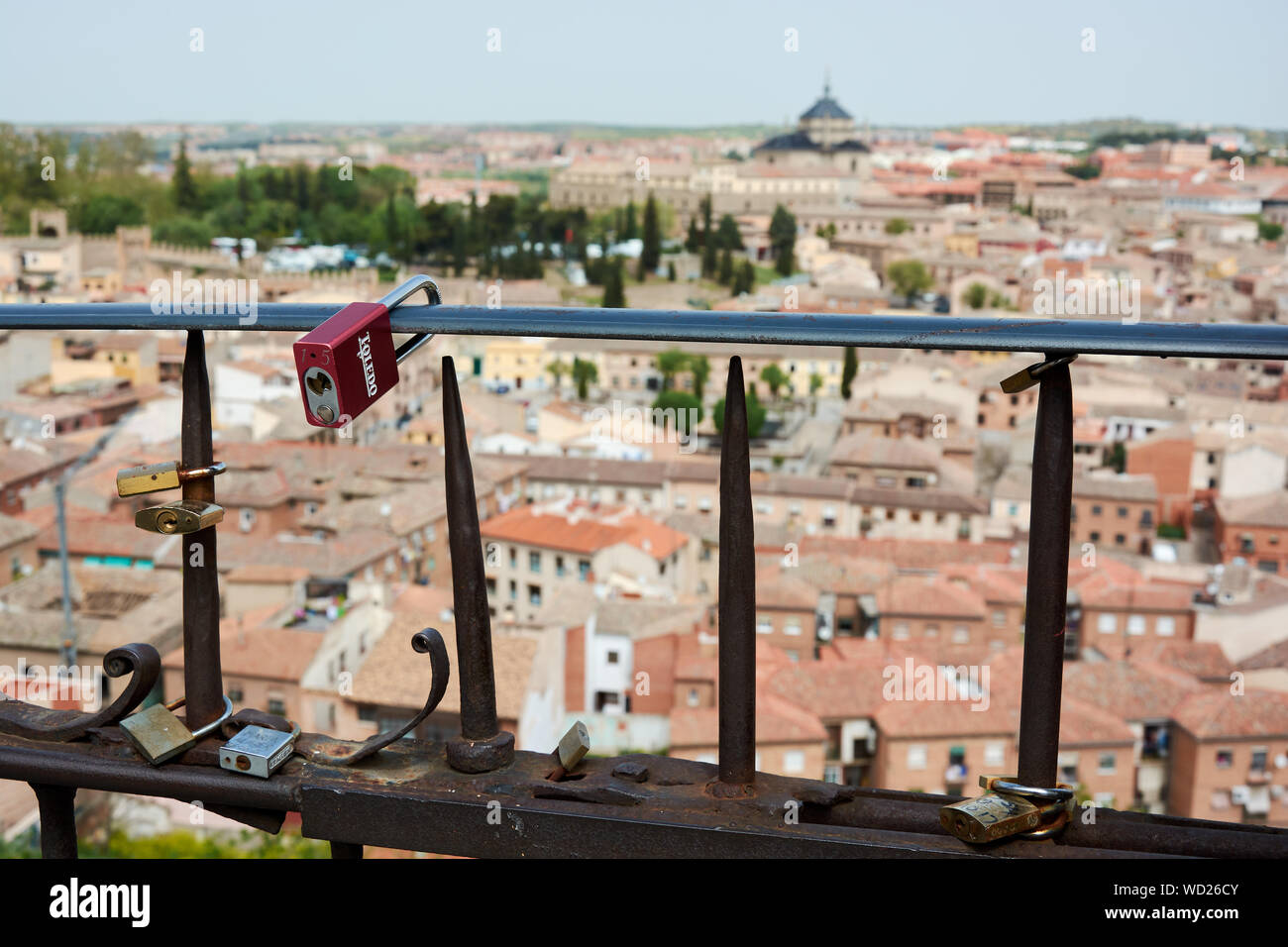 TOLEDO, SPAIN - APRIL 24, 2018: Locks of love in Toledo, hooked to a fence by lovers as a proof of eternal love. The Tavera Hospital is in the backgro Stock Photo