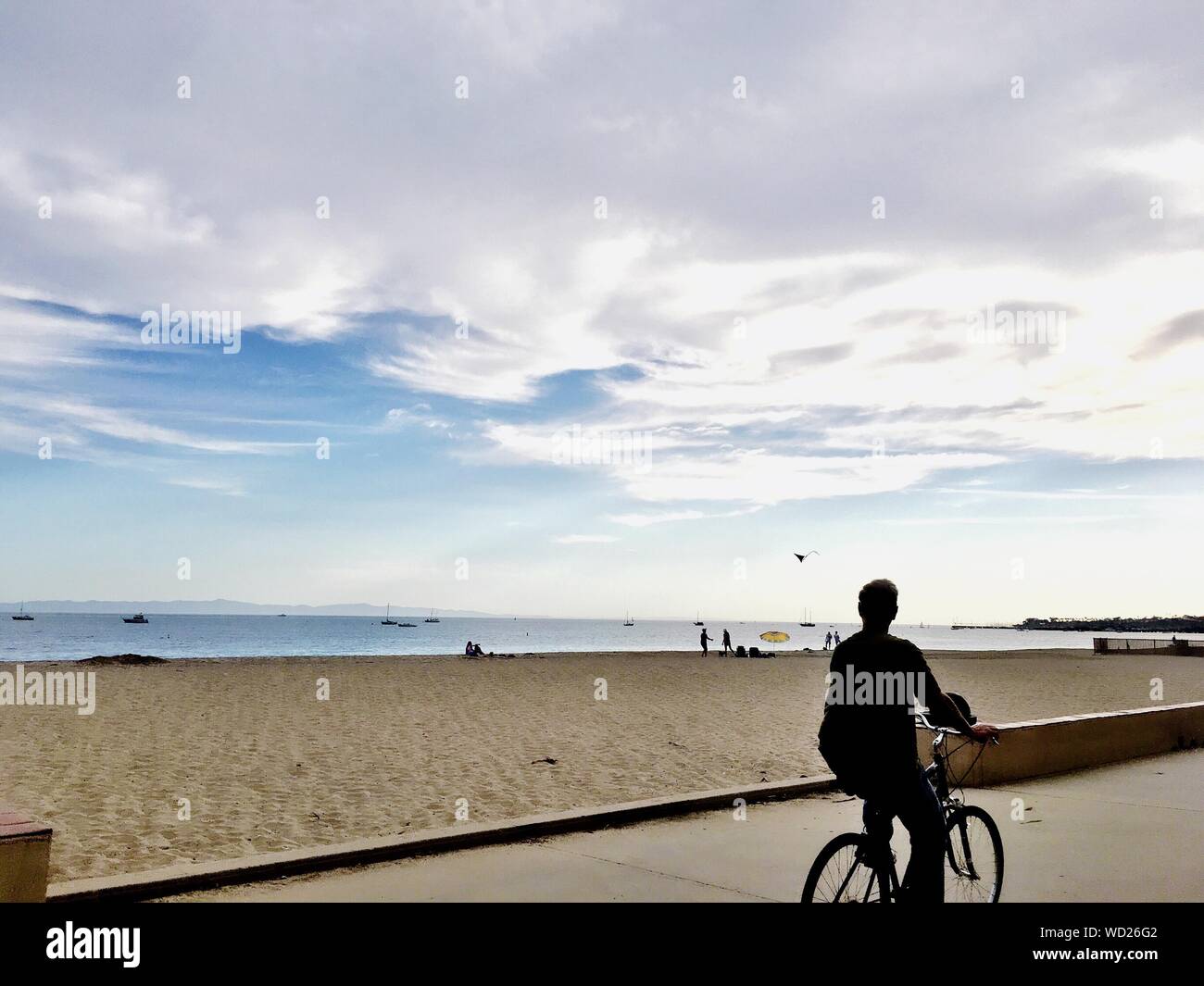 Man Riding Bicycle On Footpath Against Beach Stock Photo Alamy