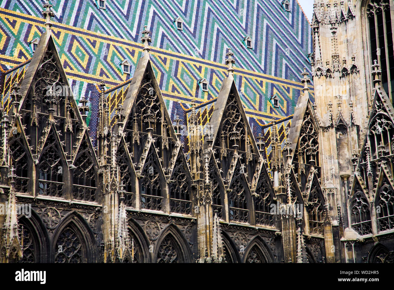 The multi-coloured geometric roof and Gothic lacework of St. Stephens Cathedral (Stephansdom) in the centre of Vienna Austria. Stock Photo