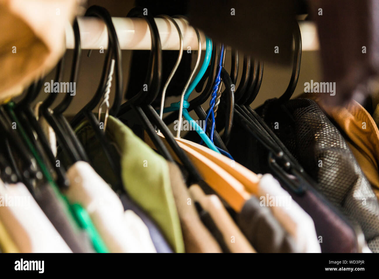 Semi organised clothes hanging in wardrobe. Stock Photo