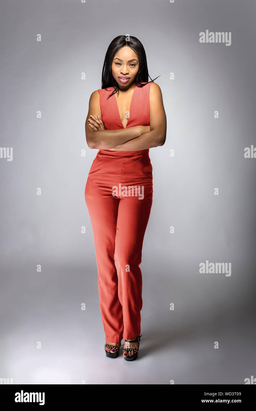 Beautiful black African American fashion model posing with pink or orange clothing in a studio for fall collection catalog. She is confidently showin Stock Photo Alamy