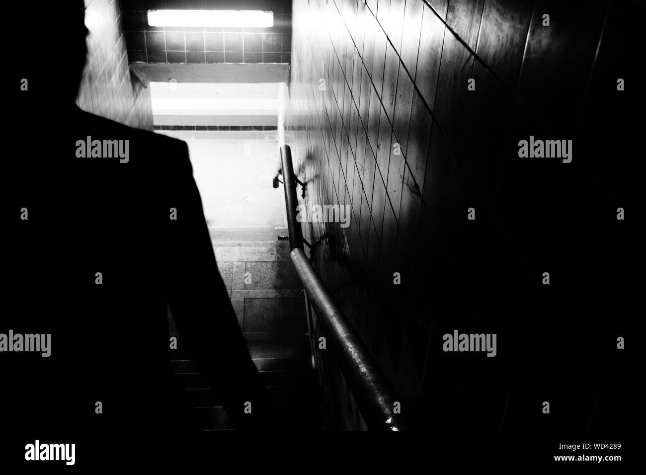 Silhouette Man Walking On Steps In Tunnel Stock Photo