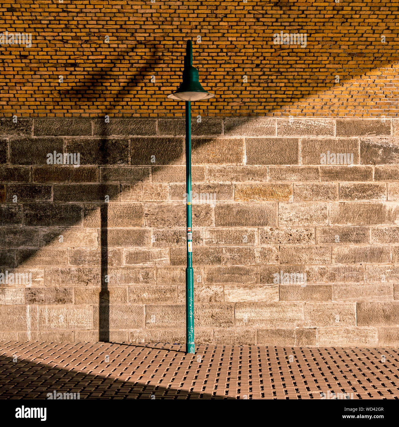 Green Street Light On Sidewalk Against Brick Wall Stock Photo