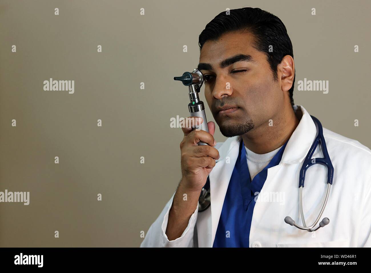 Close-up Of Doctor Holding Medical Instrument Against Gray Background Stock Photo