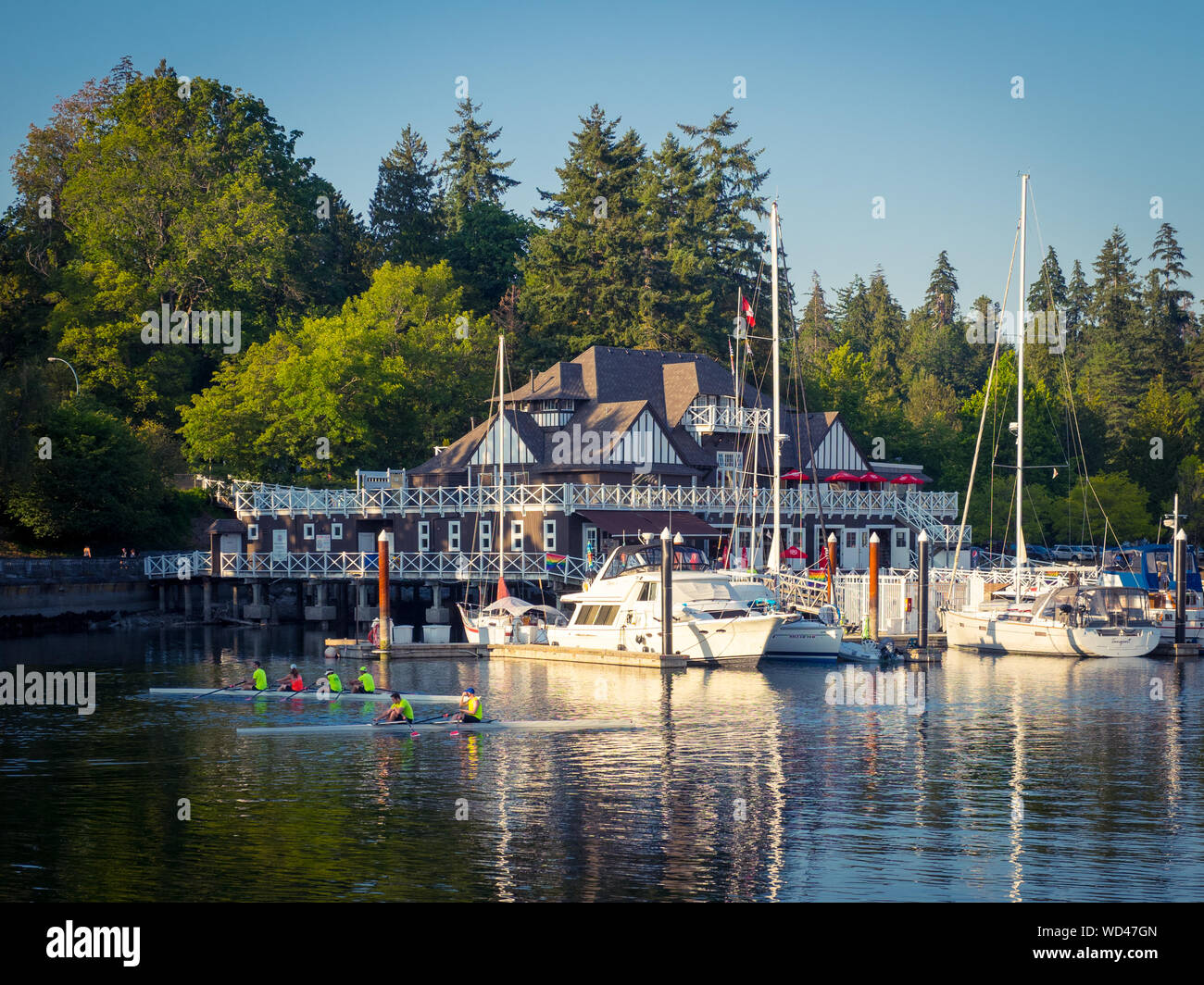 A summer view of rowers. rowboats, and yachts in front of the Vancouver Rowing Club (VRC), Stanley Park, Vancouver, British Columbia (BC), Canada. Stock Photo