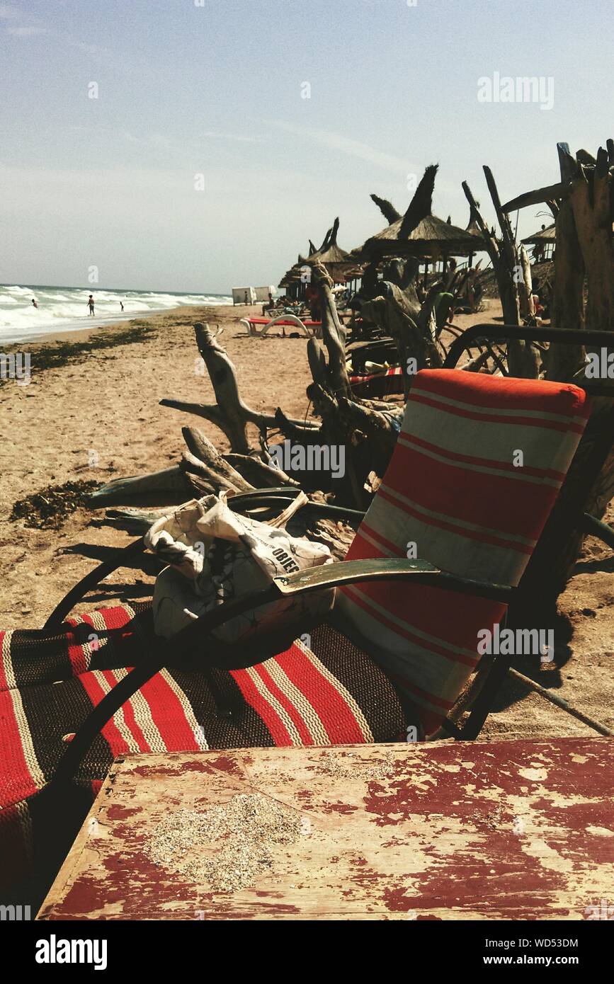 Deck Chair By Driftwood On Beach Against Sky At Vama Veche Stock Photo