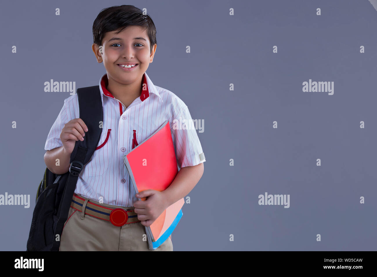 portrait of a school boy smiling with bag and books in hand Stock Photo ...