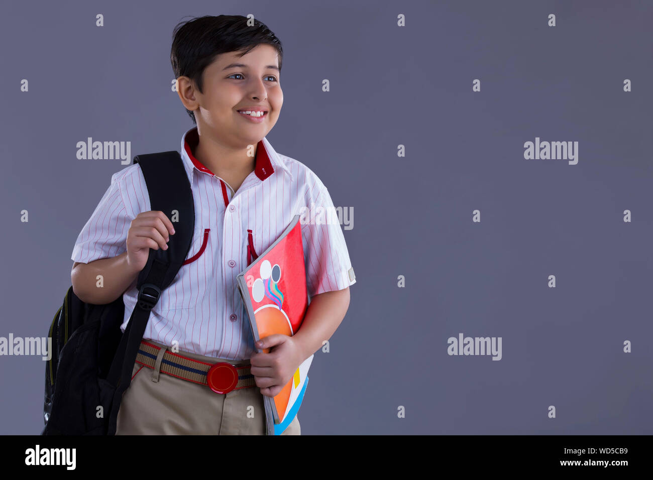 portrait of a school boy smiling with bag and books in hand Stock Photo ...