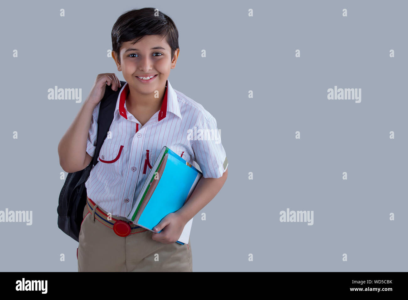 portrait of a school boy smiling with bag and books in hand Stock Photo ...