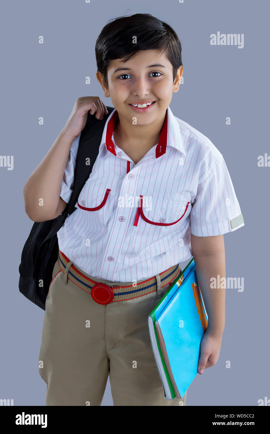 portrait of a school boy smiling with bag and books in hand Stock Photo ...