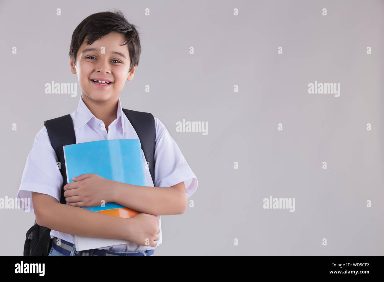 portrait of a school boy smiling with bag and books in hand Stock Photo ...