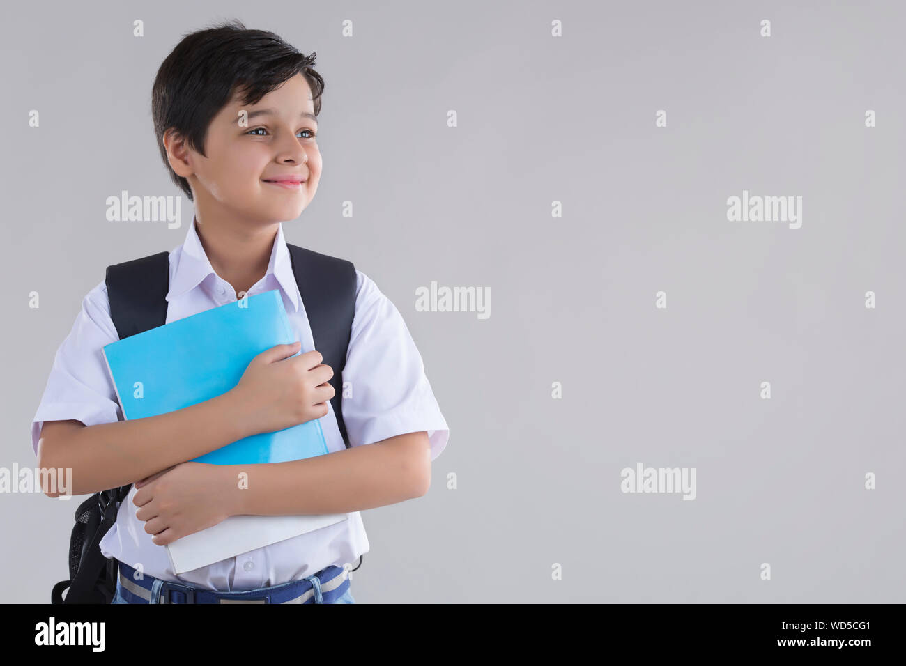 portrait of a school boy smiling with bag and books in hand Stock Photo ...