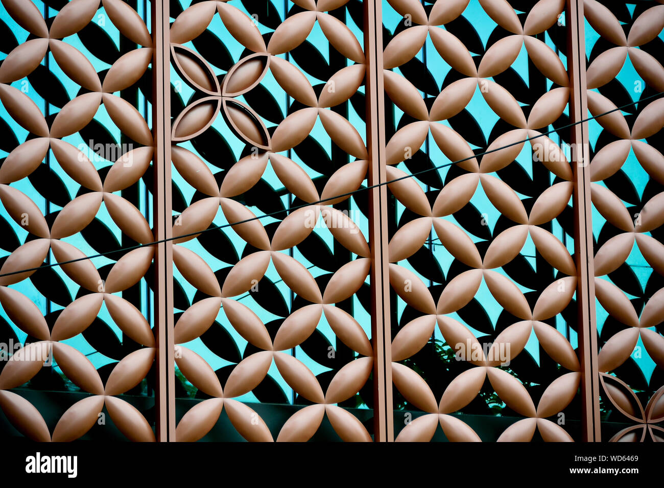 Close up of metal cladding over blue glass building exterior with repeat floral geometric patterns and strong detail as abstract background Stock Photo