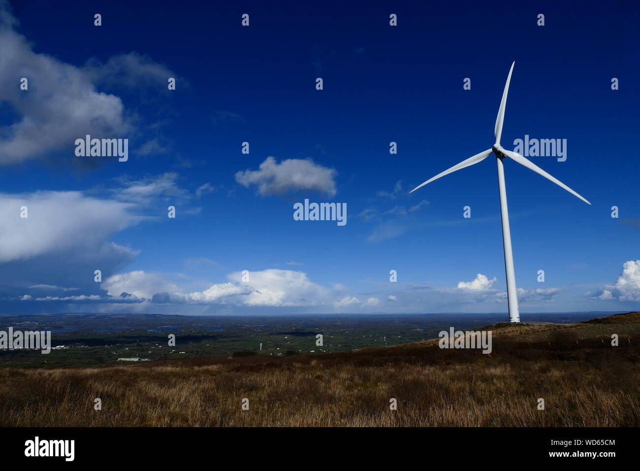Wind Turbine On Landscape Against Blue Sky Stock Photo