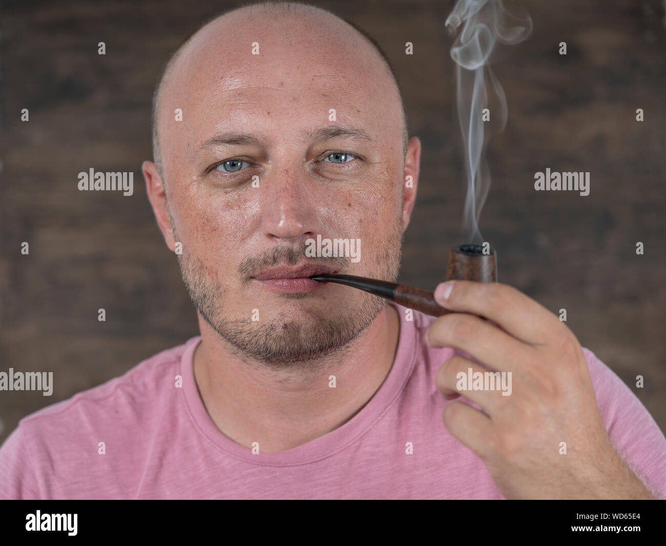 Man smoking pipe. Portrait of middle aged man indoors. Bad habits