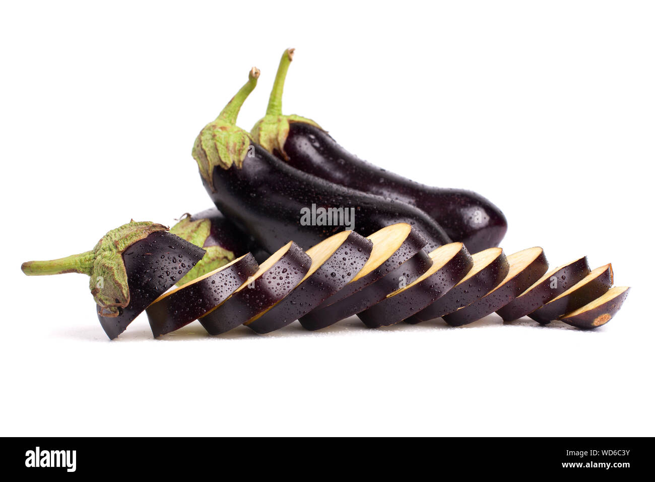 Sliced and whole eggplant in water drops on white background closeup