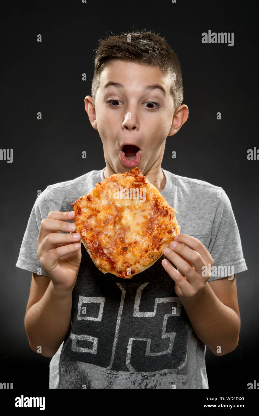 Boy Holding Pizza Against Black Background Stock Photo - Alamy