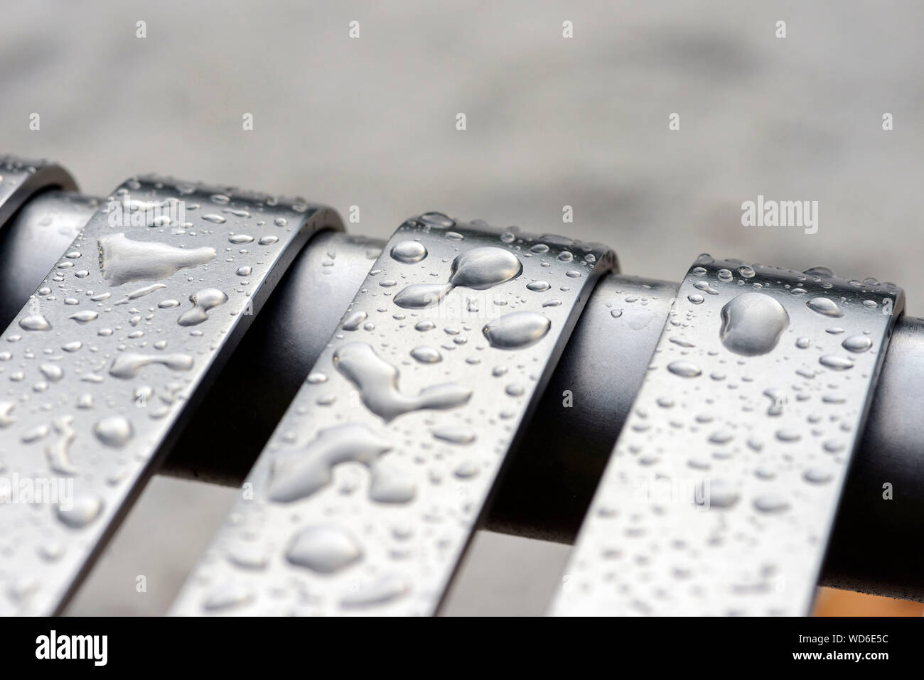 Close-up Of Wet Metallic Bench During Rainy Season Stock Photo