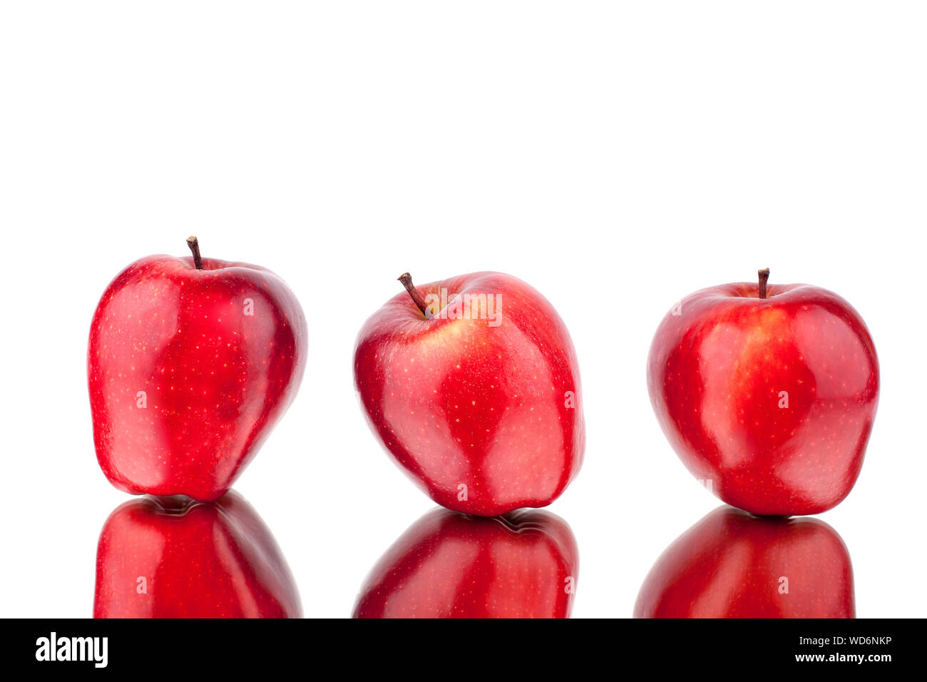 Three red apples on a white mirror background with reflection isolated close up Stock Photo
