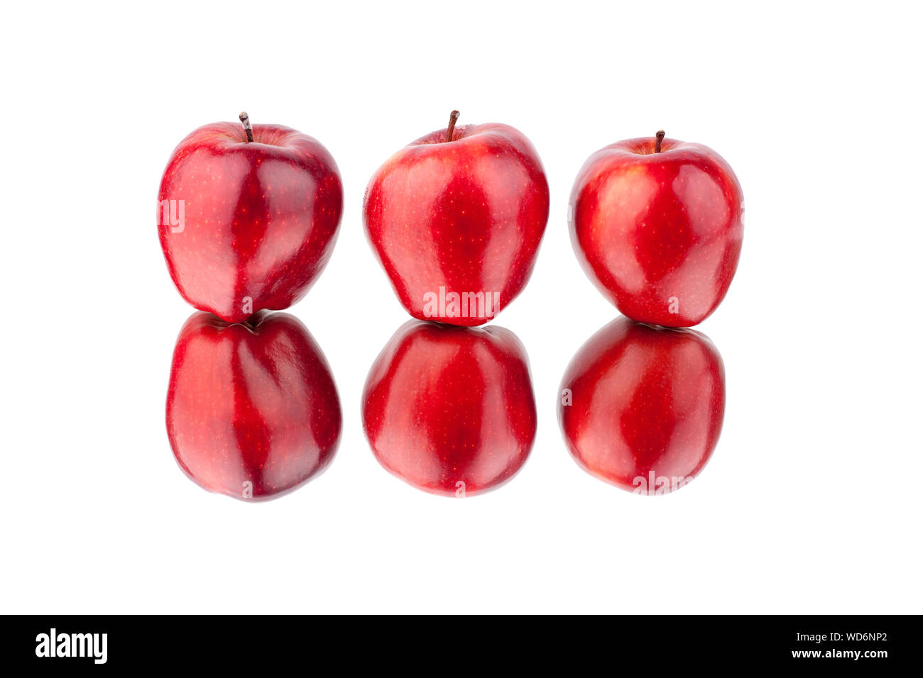 Three red apples on a white mirror background with reflection isolated close up Stock Photo