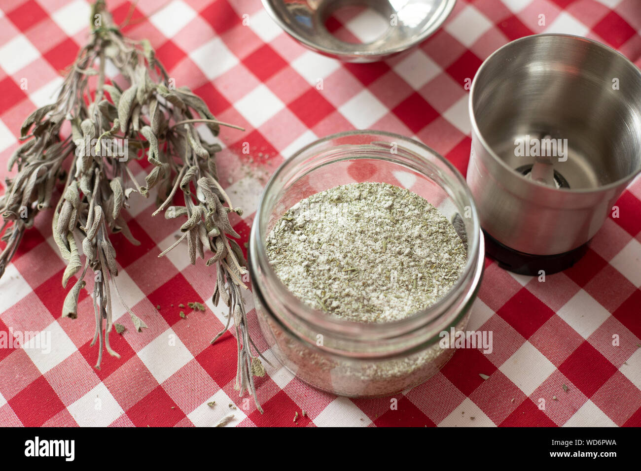 Glass vase containing aromatics herbs - like dried sage and rosemary - mixed with sea salt using a blender, an homemade seasoning for everyday cooking Stock Photo