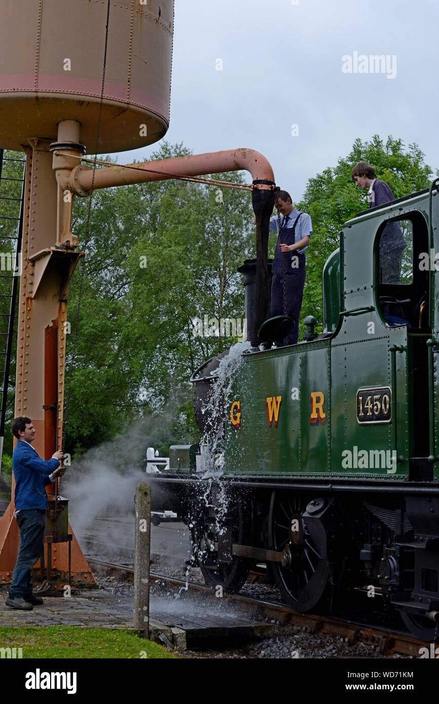 Young volunteer staff refill teh water tanks of GWR 14XX class 1450 tank engine at Didcot Railway Centre, Oxfordshire Stock Photo