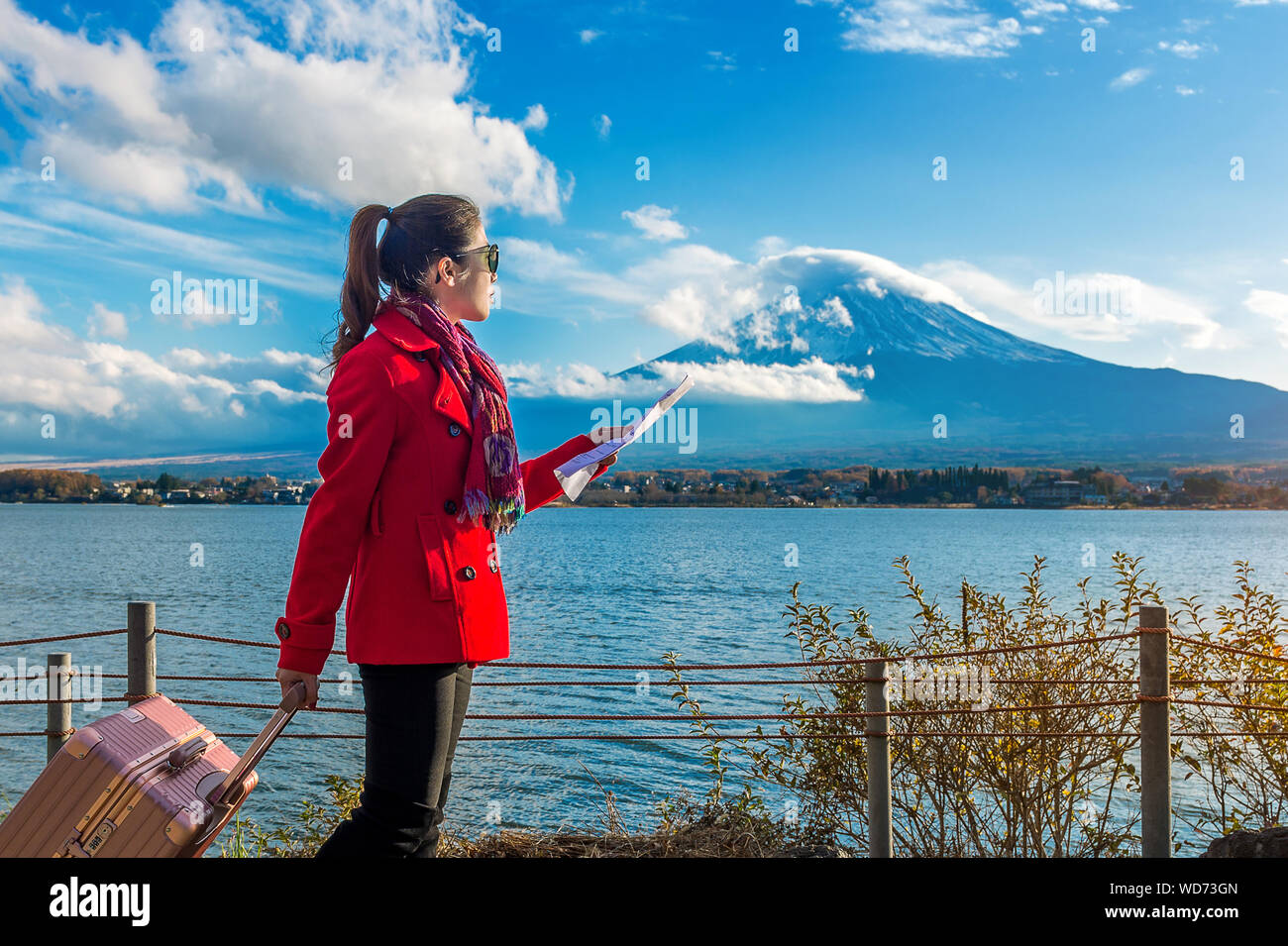 Young Woman With Luggage Standing By Lake Kawaguchi Holding Map Stock Photo