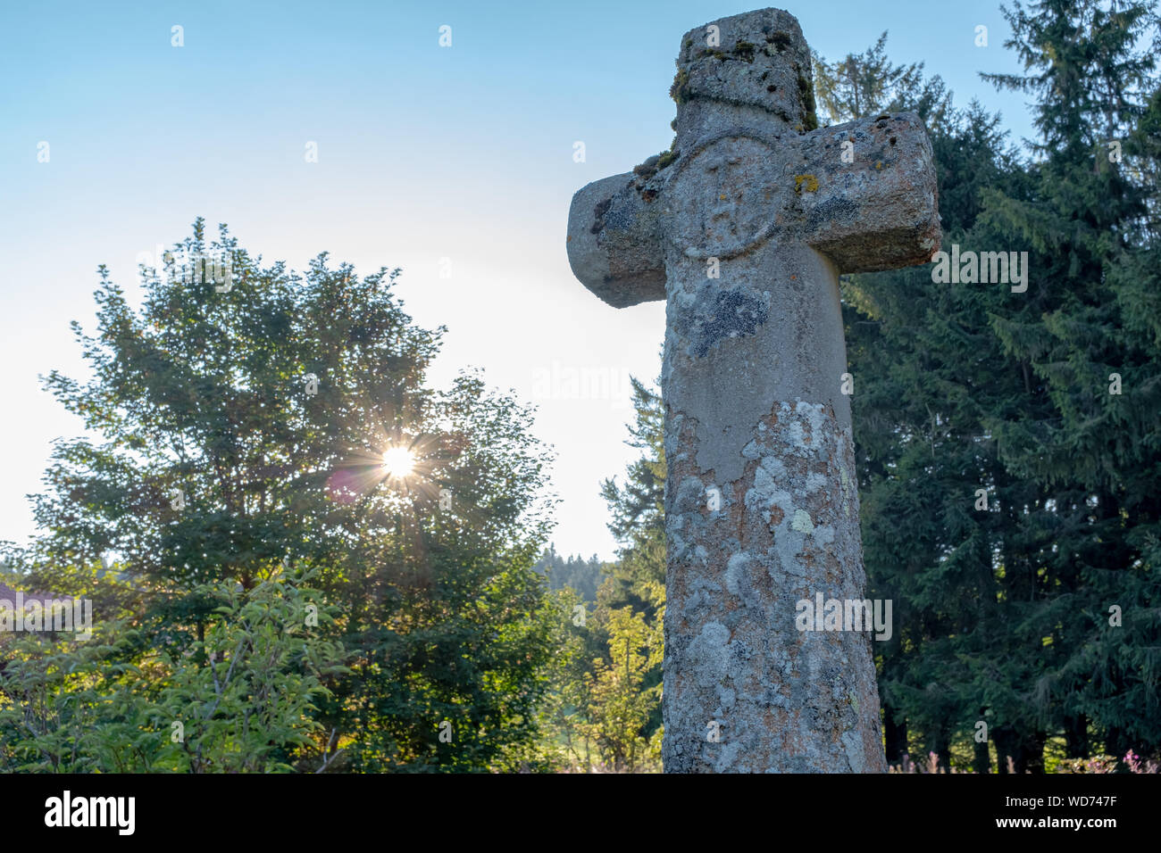 Wayside cross taken at sunrise with sun rays going through a tree in the background, Mont Pilat, France Stock Photo