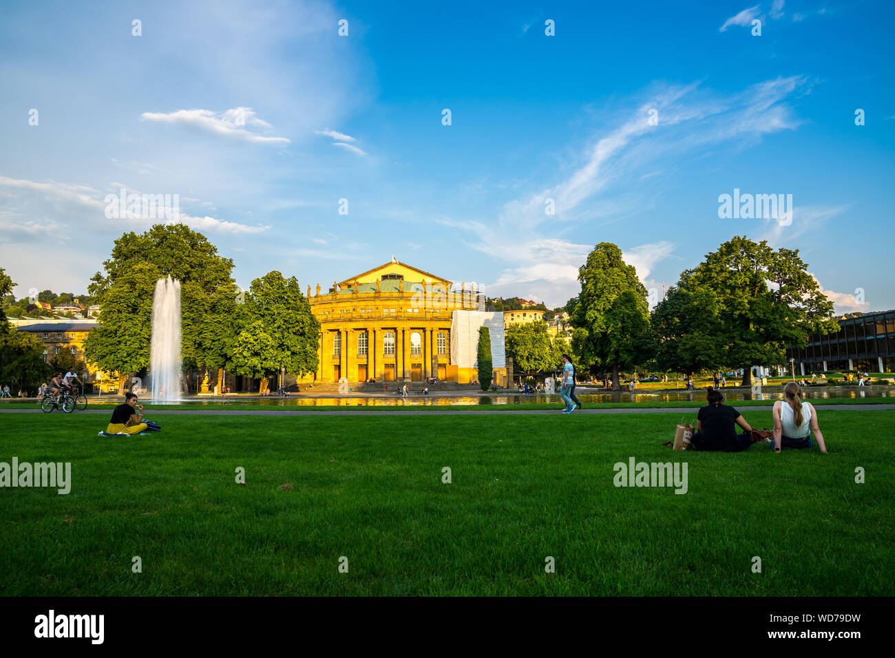 Stuttgart, Germany, August 25, 2019, People enjoy relaxing on green grass meadow in downtown stuttgart, palace garden, with view to ancient opera hous Stock Photo