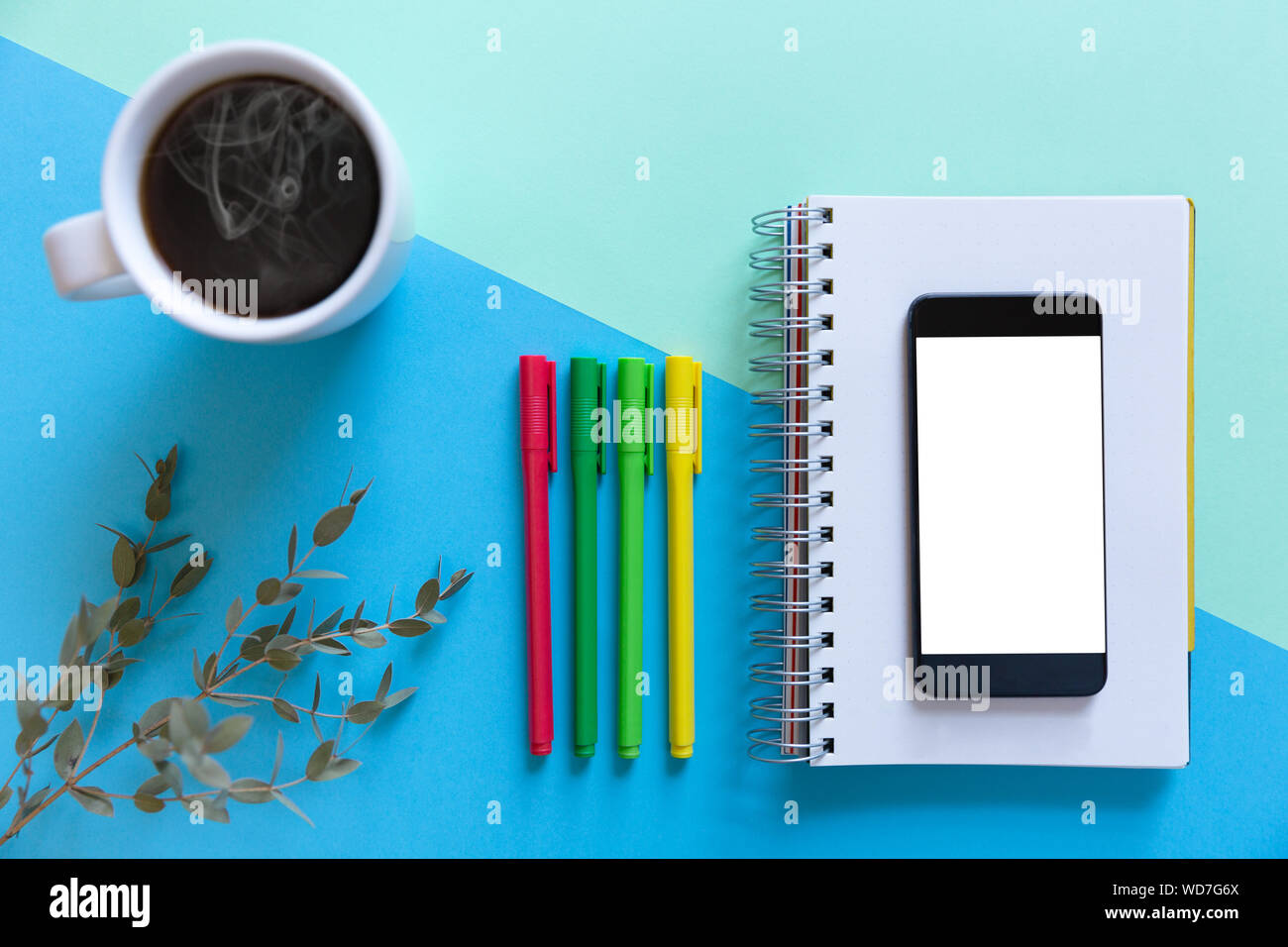 Smartphone, notebook, color pencils and coffee on blue paper background. Business start-up and back to schools concept Stock Photo