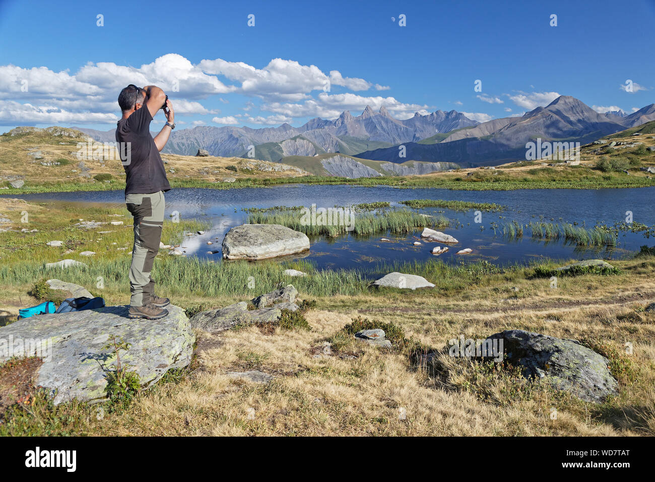 SAINT-SORLIN, FRANCE, August 9, 2019 : Photographer shoots a beautiful landscape on a mountain lake shore. Stock Photo