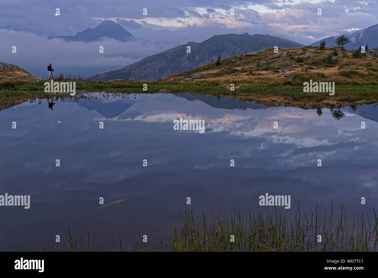 SAINT-SORLIN, FRANCE, August 10, 2019 : Photographer shoots a landscape of a mountain lake in the first light of dawn. Stock Photo