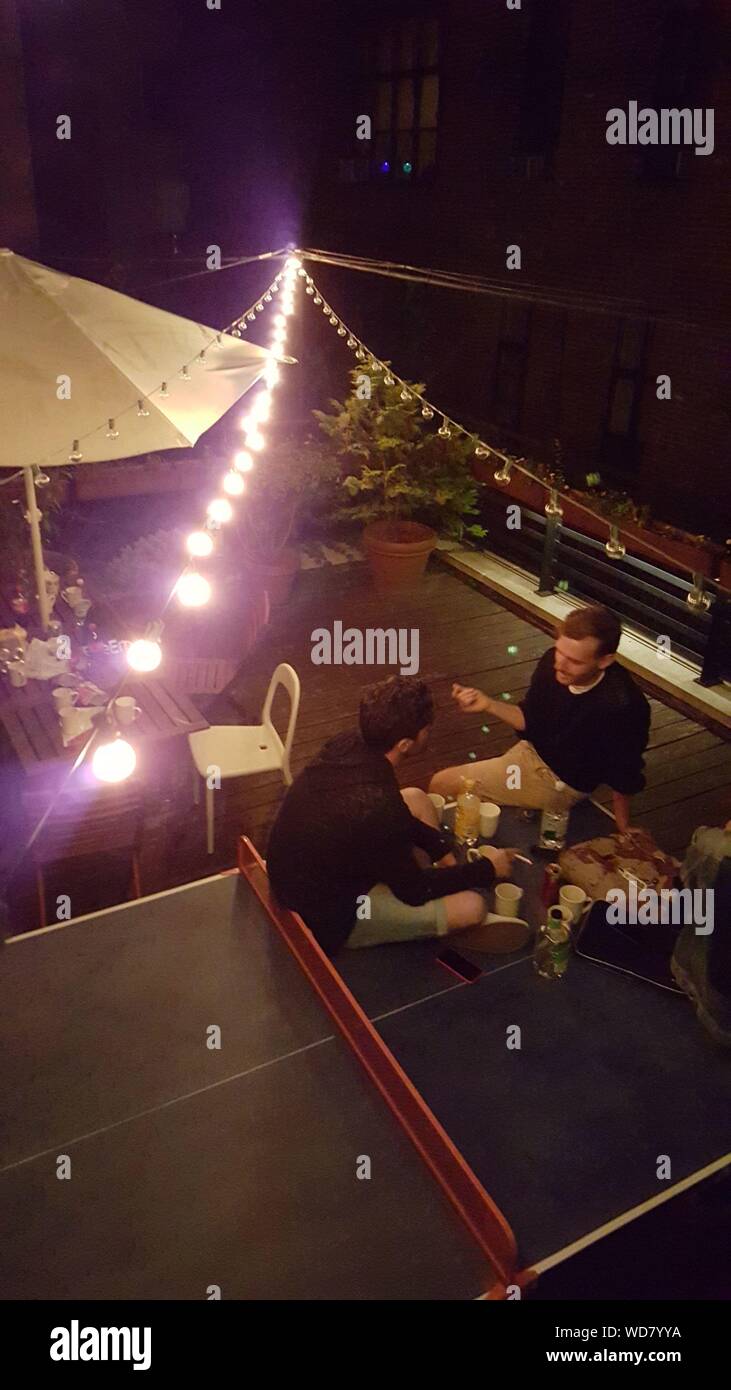 High Angle View Of Friends Communicating Over Dinner At Night Stock Photo