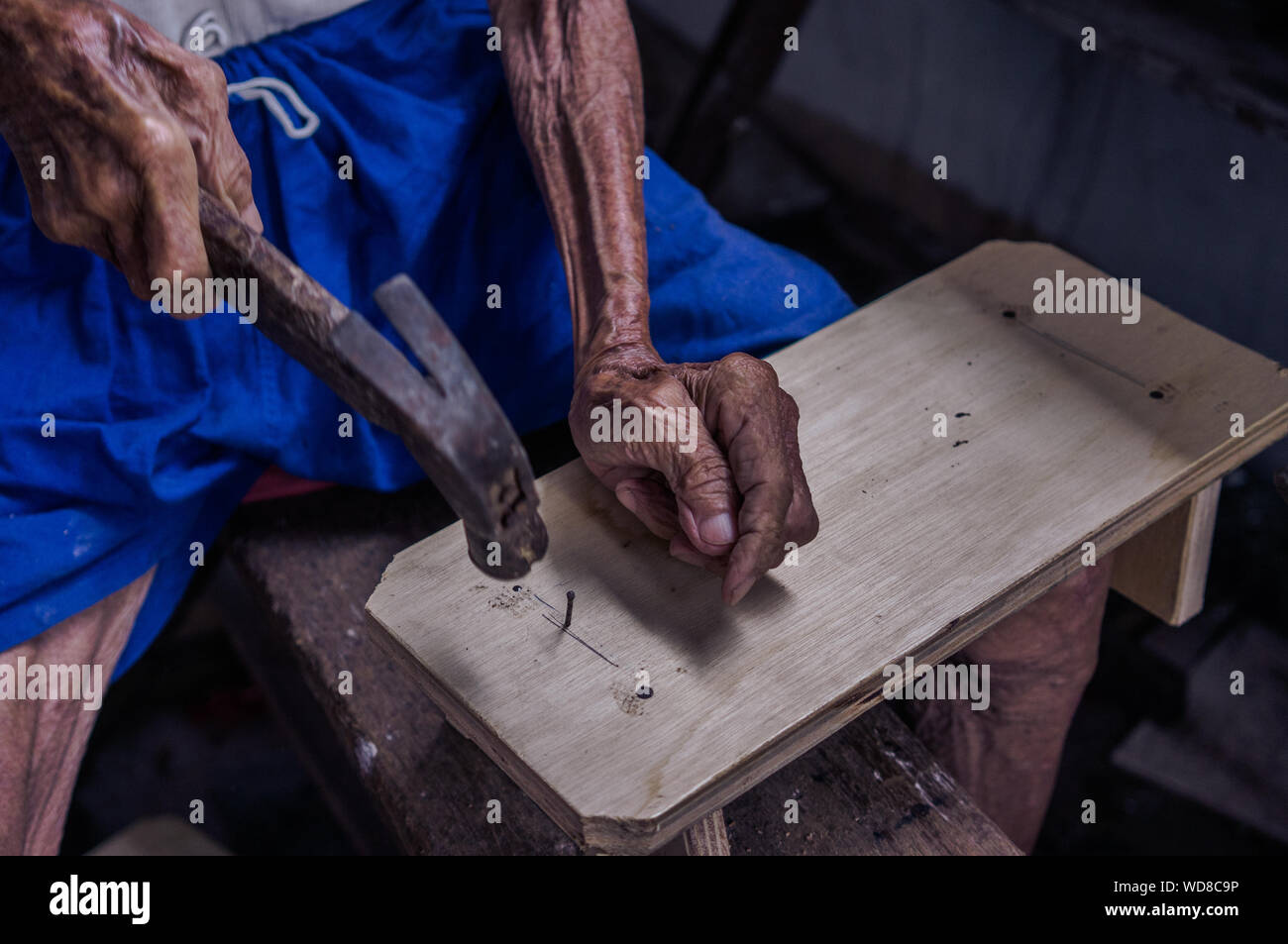 High Angle View Of Man Hammering Nail On Wood Stock Photo
