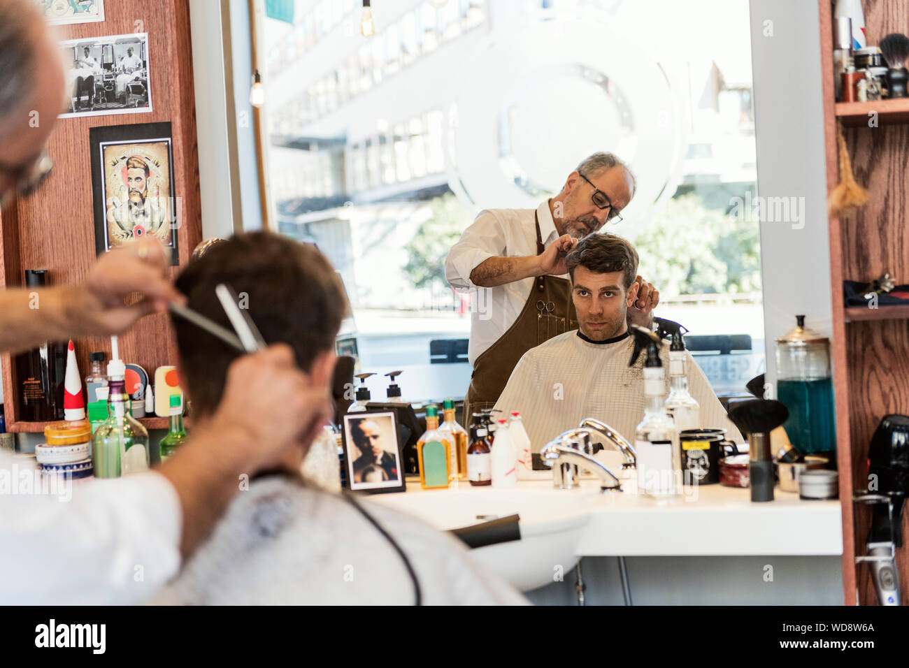 Reflection of barber cutting young man´s hair in mirror Stock Photo Alamy