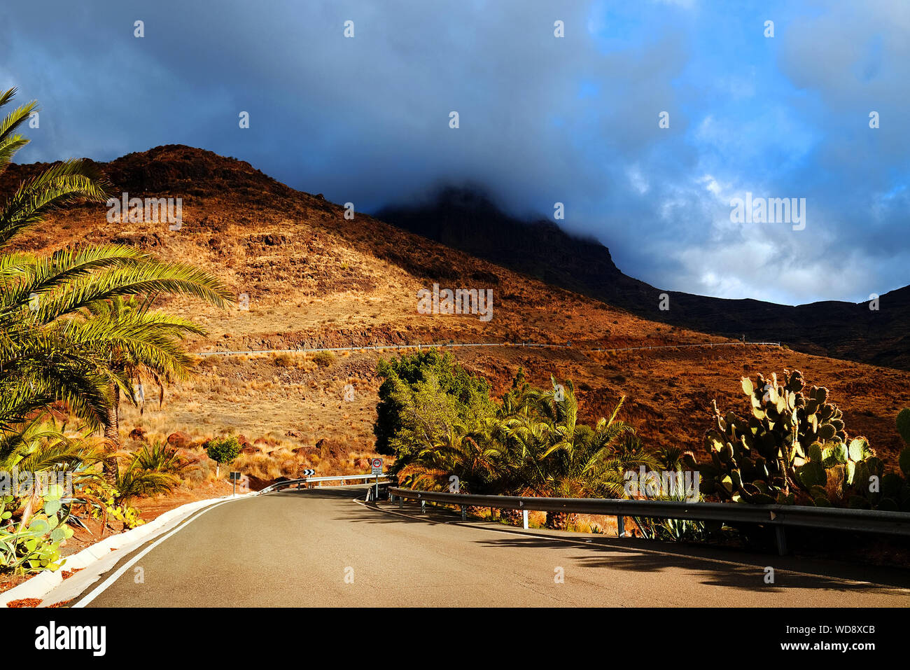 Diminishing Perspective Of Road Passing Through Mountains Against Cloudy Sky Stock Photo