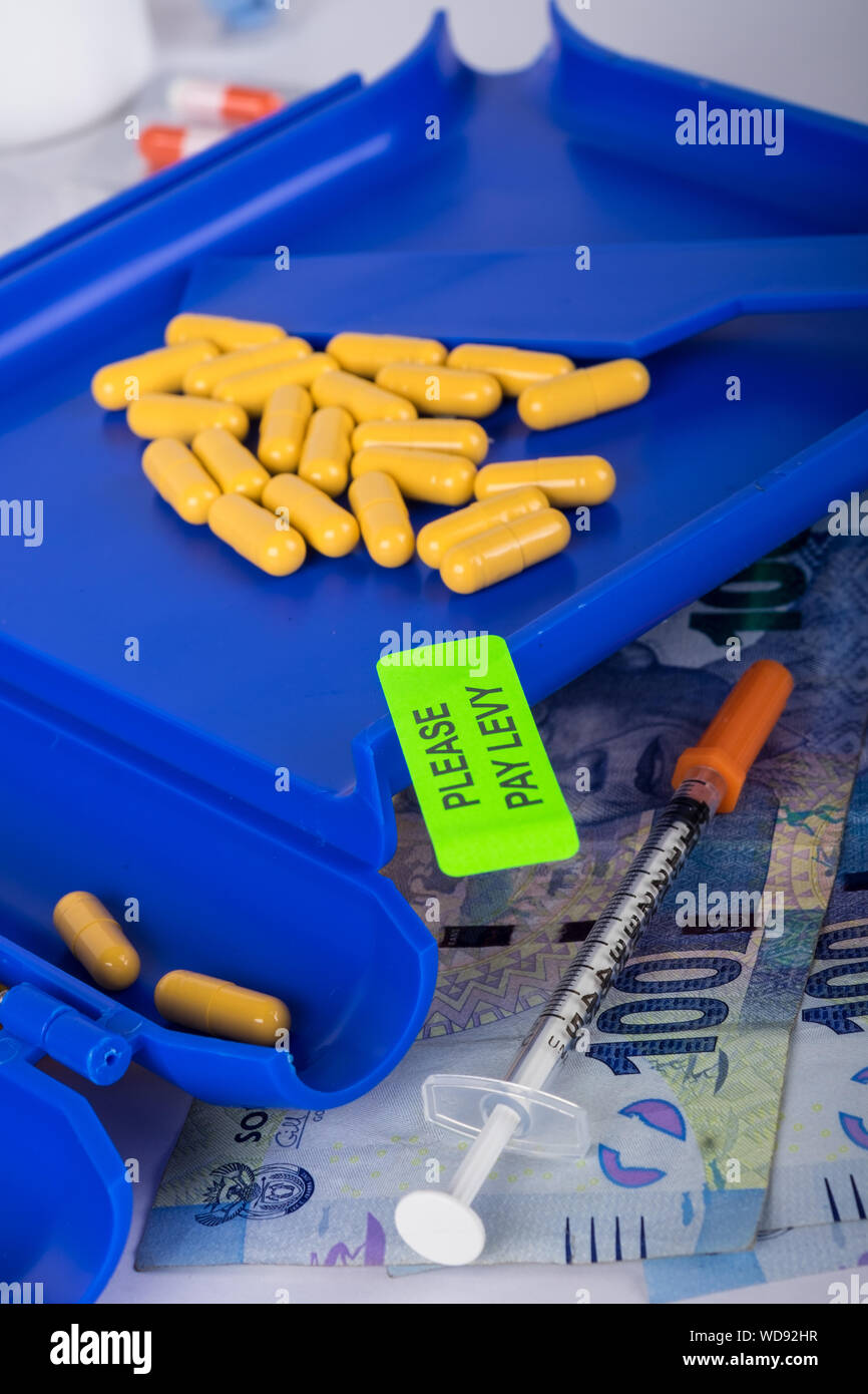 Tablets counter with tablets on and with a bright green sticker on warning to please pay levy on, South African rands in the foreground. Stock Photo