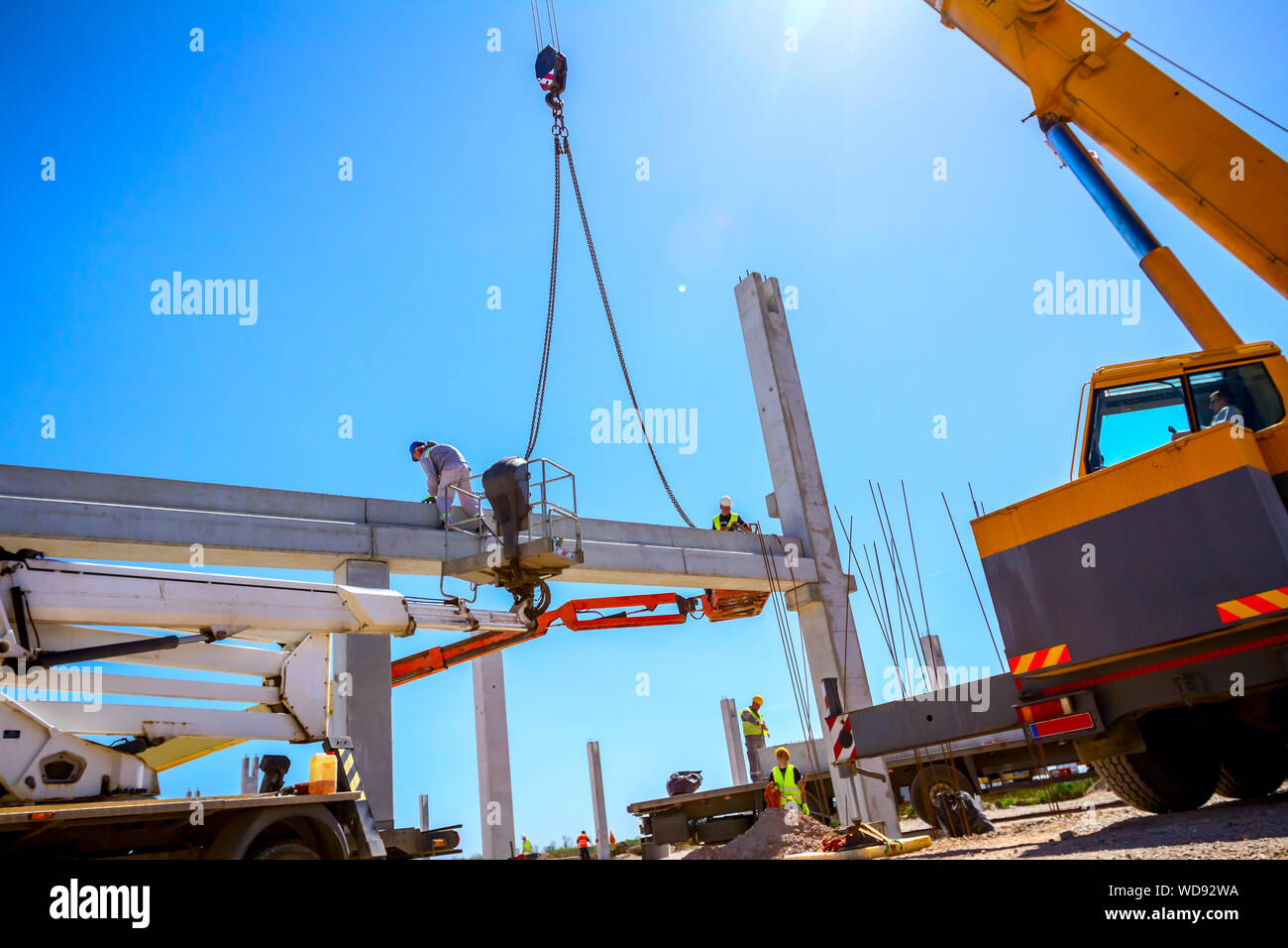 Worker is helping mobile crane to manage concrete joist for assembly ...