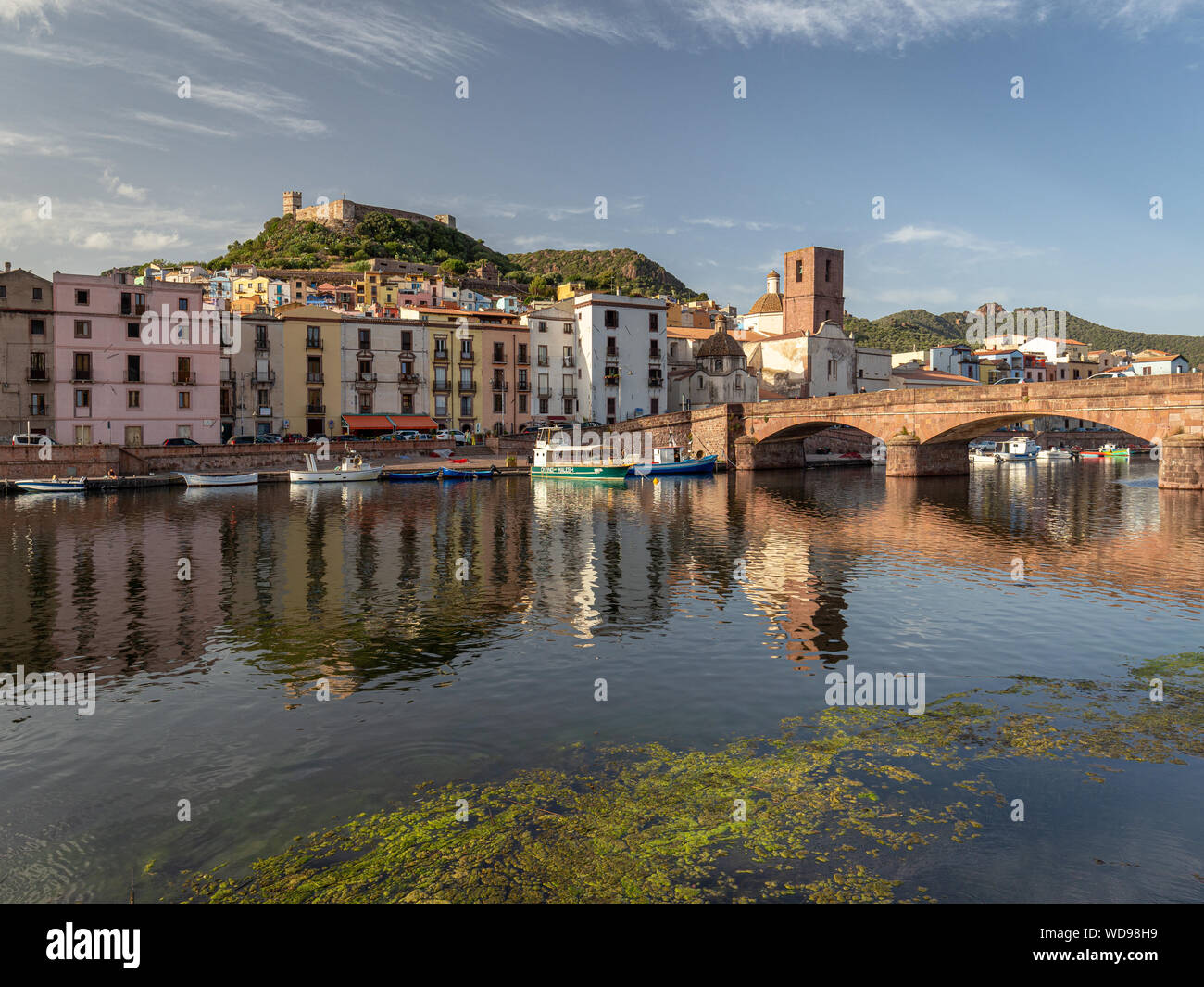 Medieval town Bosa during sunset. Bridge and colorful houses reflected in Temo river. Castle over the city Stock Photo