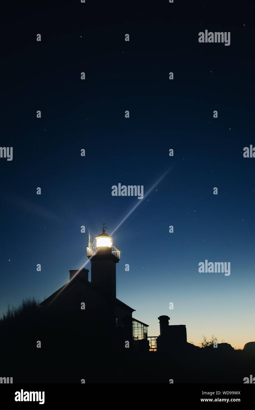Vertical low angle silhouette shot of a lighted tower under a starry ...