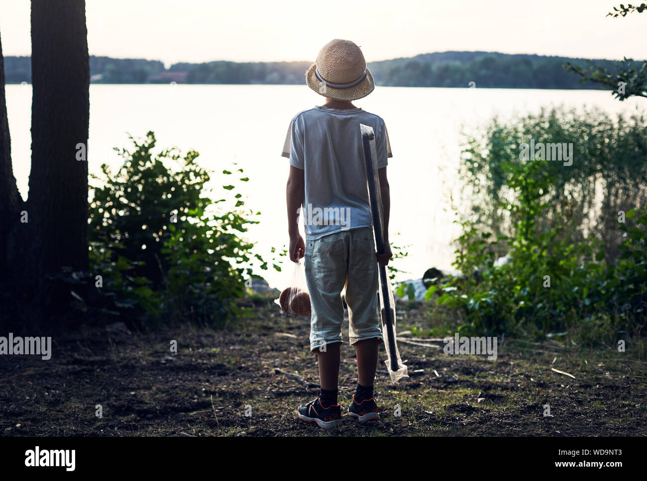 Boy holding fishing rod by lake Stock Photo