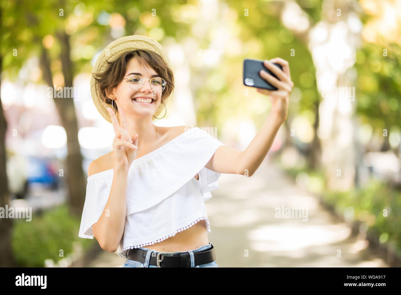Portrait of young beautiful woman walking in the park take a selfie by ...