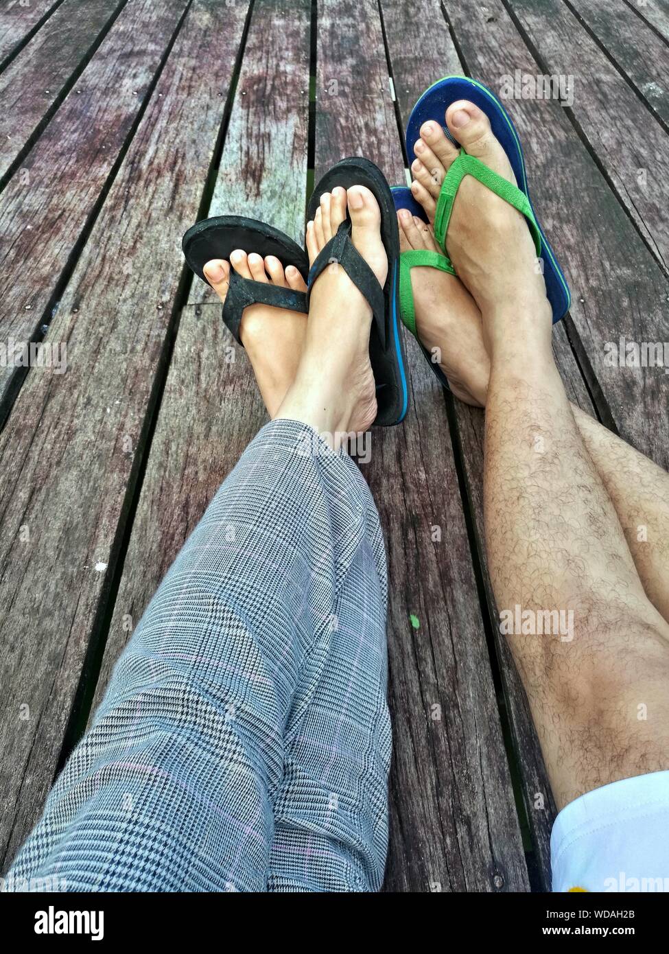 Low Section Of Couple Wearing Flip-flop On Boardwalk Stock Photo - Alamy