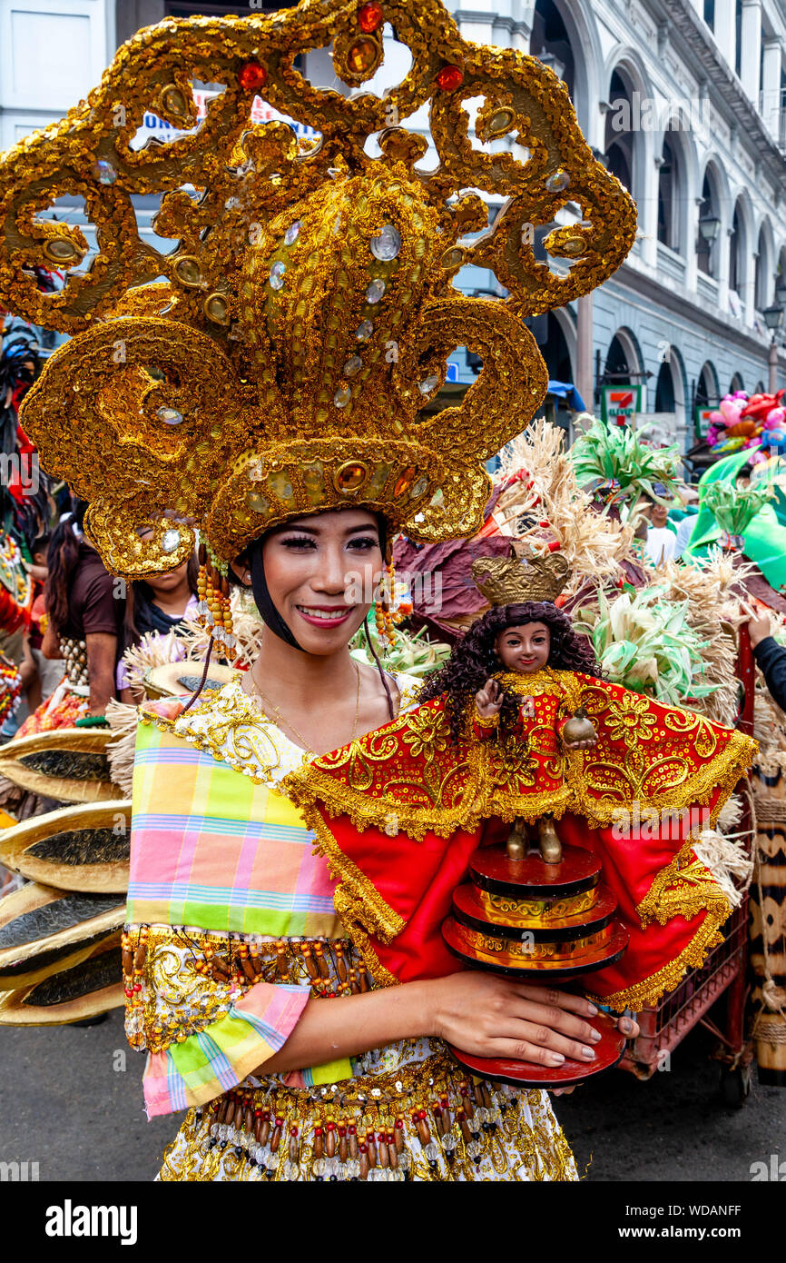 A Young Filipino Woman Walks Through The Streets Holding A Santo Nino Statue, The Dinagyang Festival, Iloilo City, Panay Island, The Philippines Stock Photo
