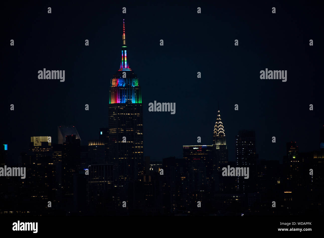 Manhattan at night with Empire State Building in Pride rainbow colors and Chrysler Building right next to it Stock Photo